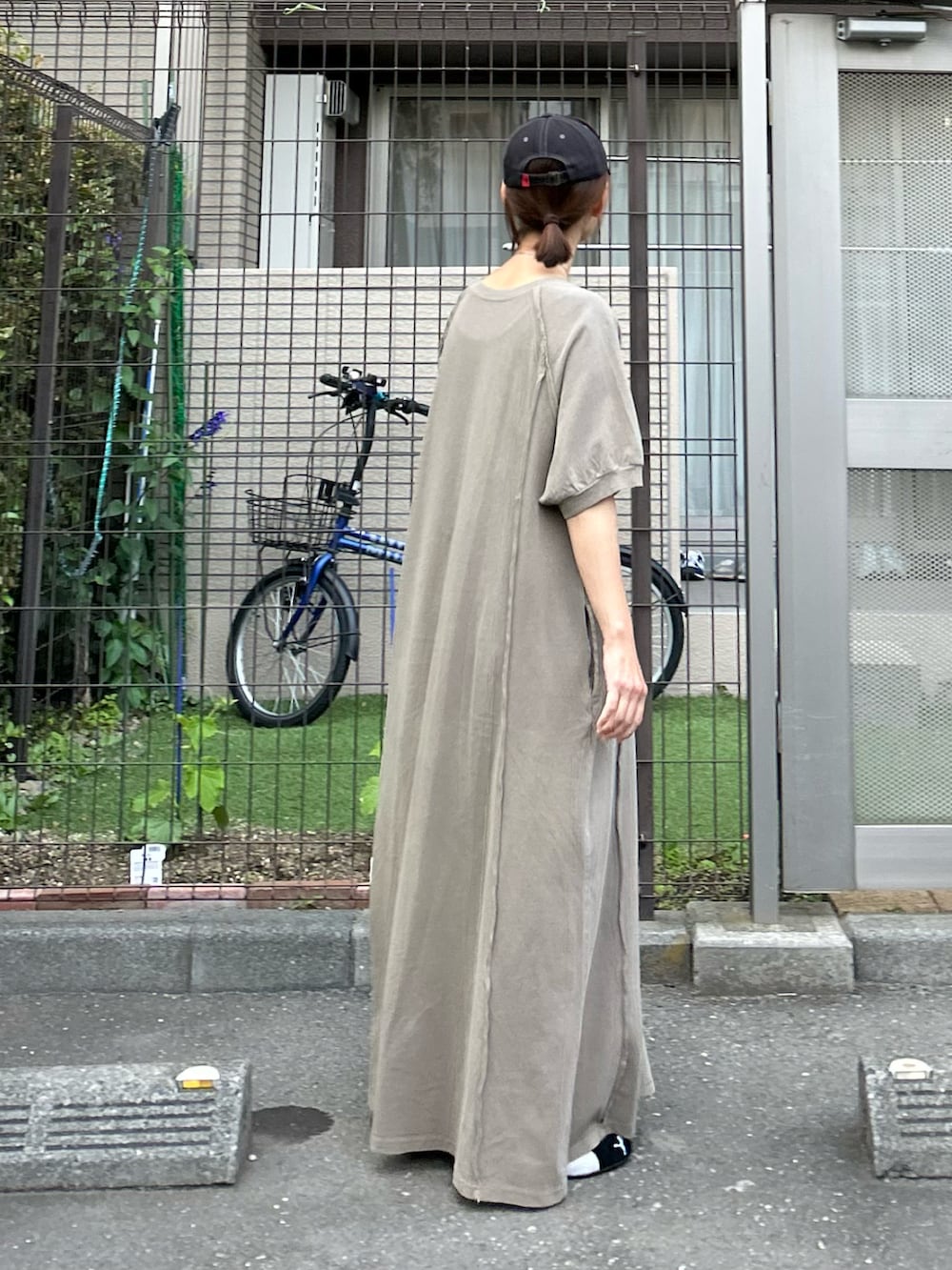 グリーン系のワンピース、ブラック系のショルダーバッグ、ブラック系のスニーカーを着用したレディースの春コーディネートの4枚目の写真