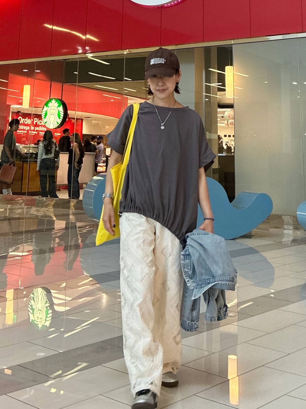 グレー系のTシャツ/カットソー、ホワイト系のスラックス、シルバー系のスニーカーを着用したレディースの春コーディネートの4枚目の写真