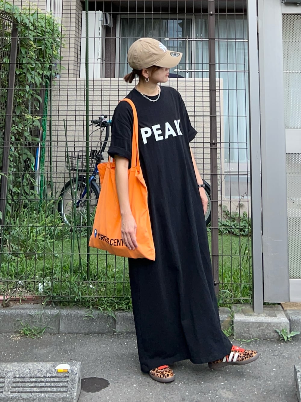 ブラック系のワンピース、オレンジ系のトートバッグ、ブラック系のスニーカーを着用したレディースの夏コーディネートの2枚目の写真