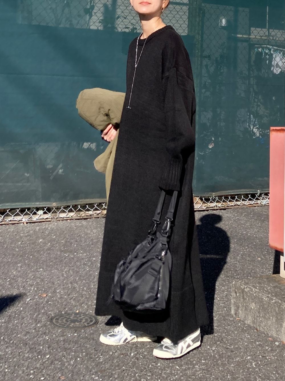 ブラック系のワンピース、ブラック系のショルダーバッグ、シルバー系のスニーカーを着用したレディースの冬コーディネートの3枚目の写真