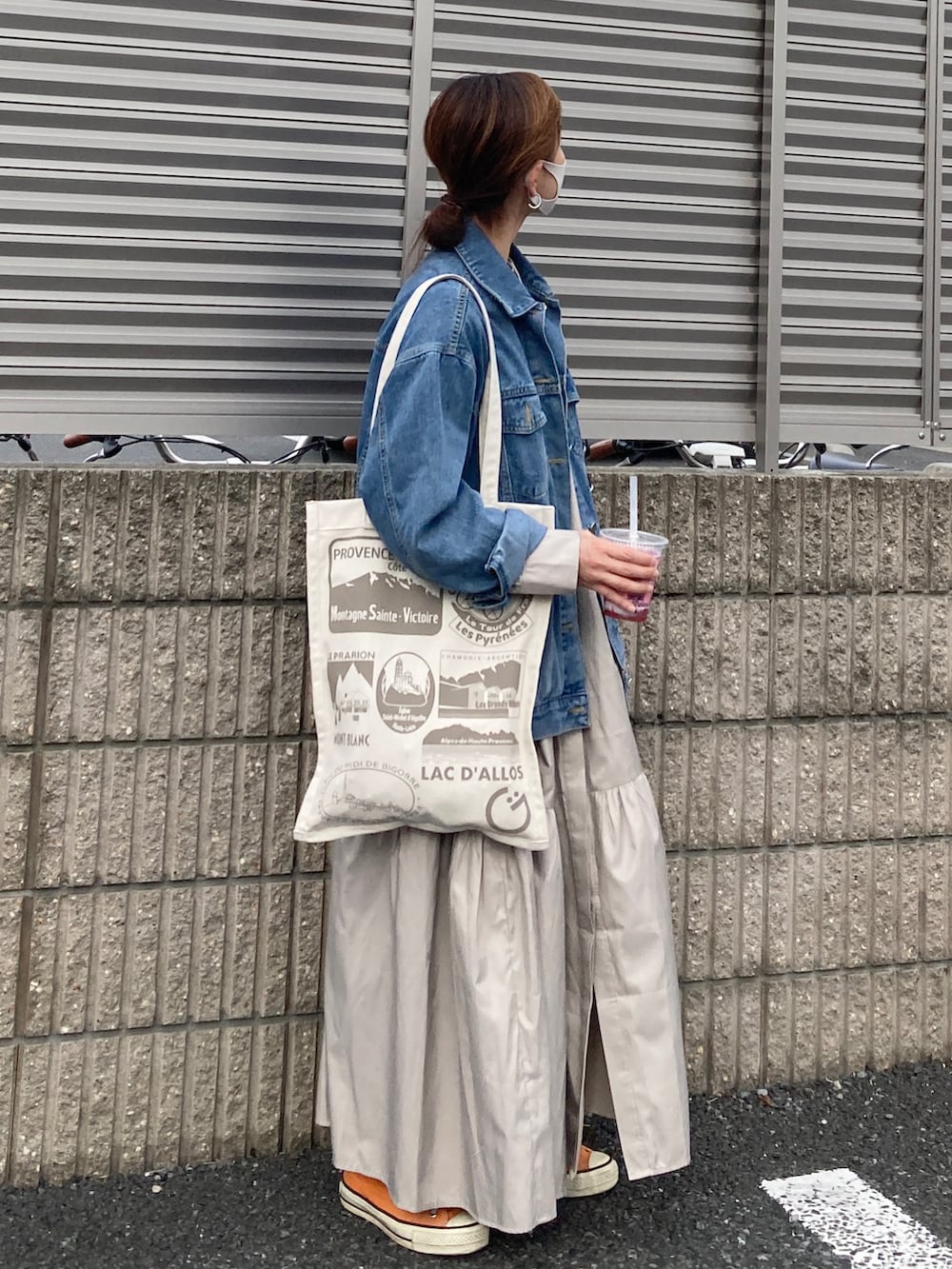 ブルー系のデニムジャケット、ベージュ系のシャツワンピース、ベージュ系のバッグを着用したレディースの春コーディネートの2枚目の写真