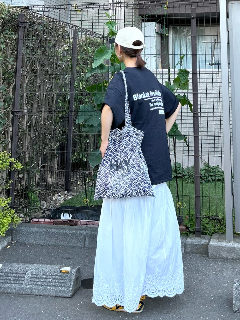ブラック系のTシャツ/カットソー、ホワイト系のスカート、イエロー系のスニーカーを着用したレディースの夏コーディネートの4枚目の写真