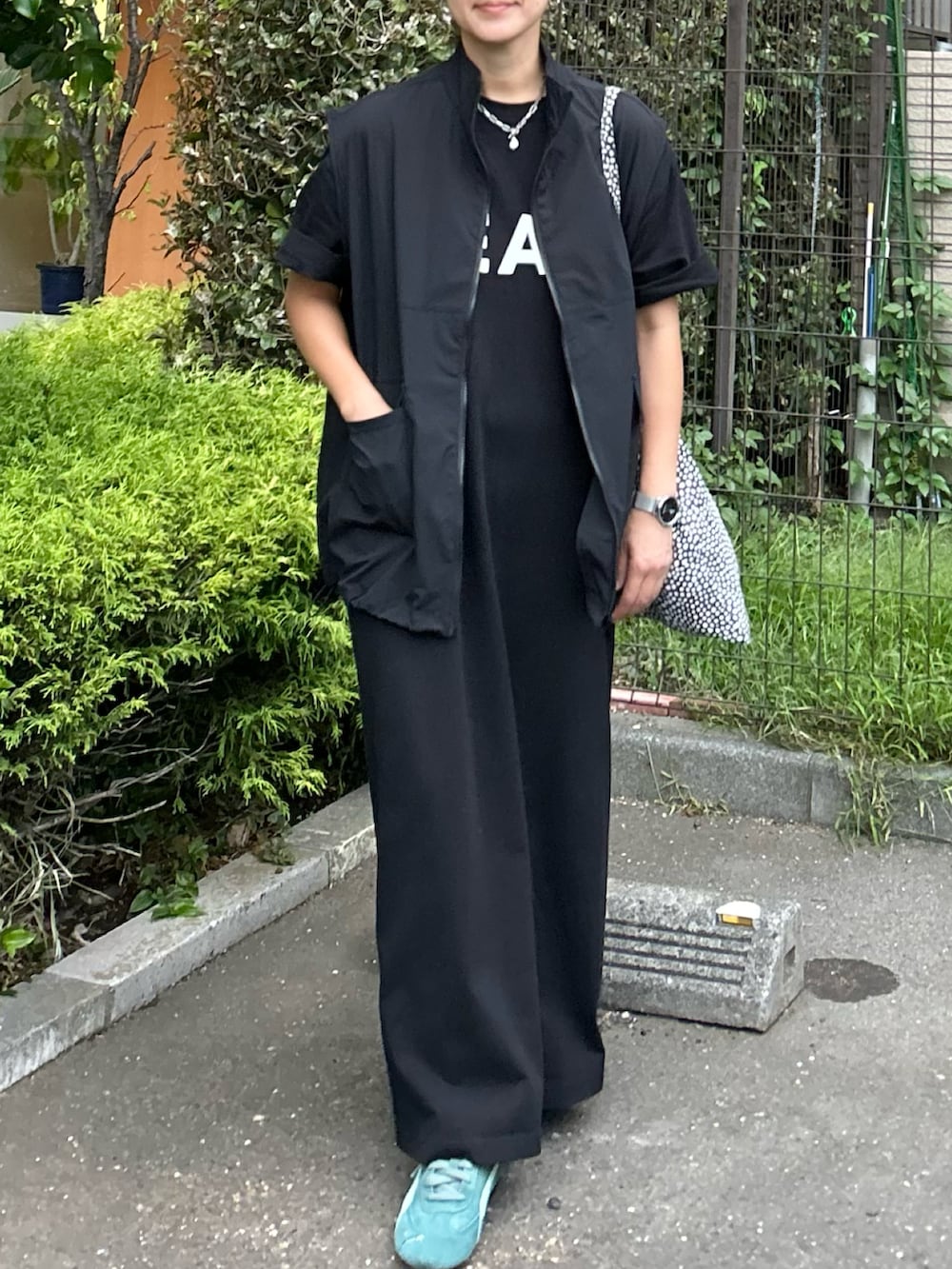 ブラック系のベスト、ブラック系のワンピース、グリーン系のスニーカーを着用したレディースの秋コーディネートの4枚目の写真