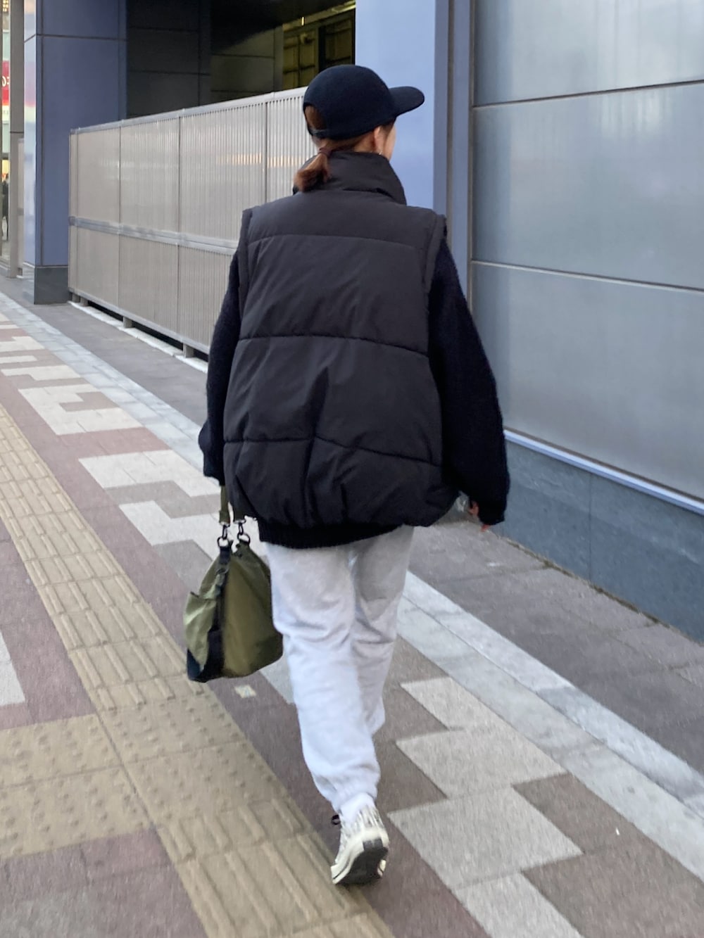 ブラック系のダウンベスト、グリーン系のショルダーバッグ、ブラック系のニット/セーターを着用したレディースの冬コーディネートの2枚目の写真