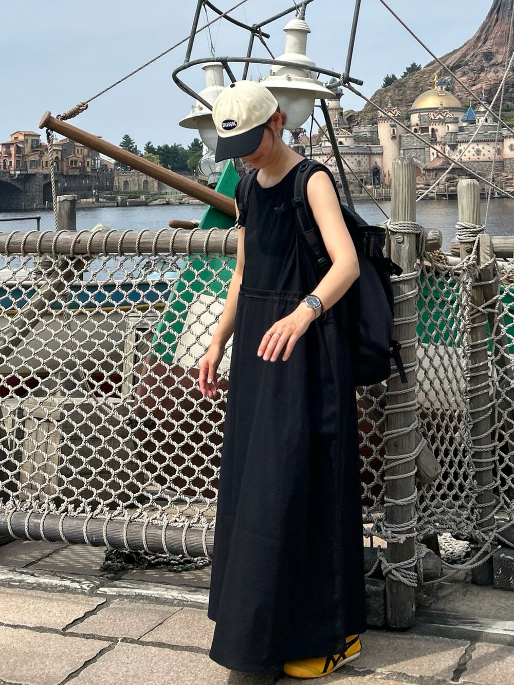 ブラック系のワンピース、イエロー系のスニーカー、ブラック系のキャップを着用したレディースの夏コーディネートの3枚目の写真