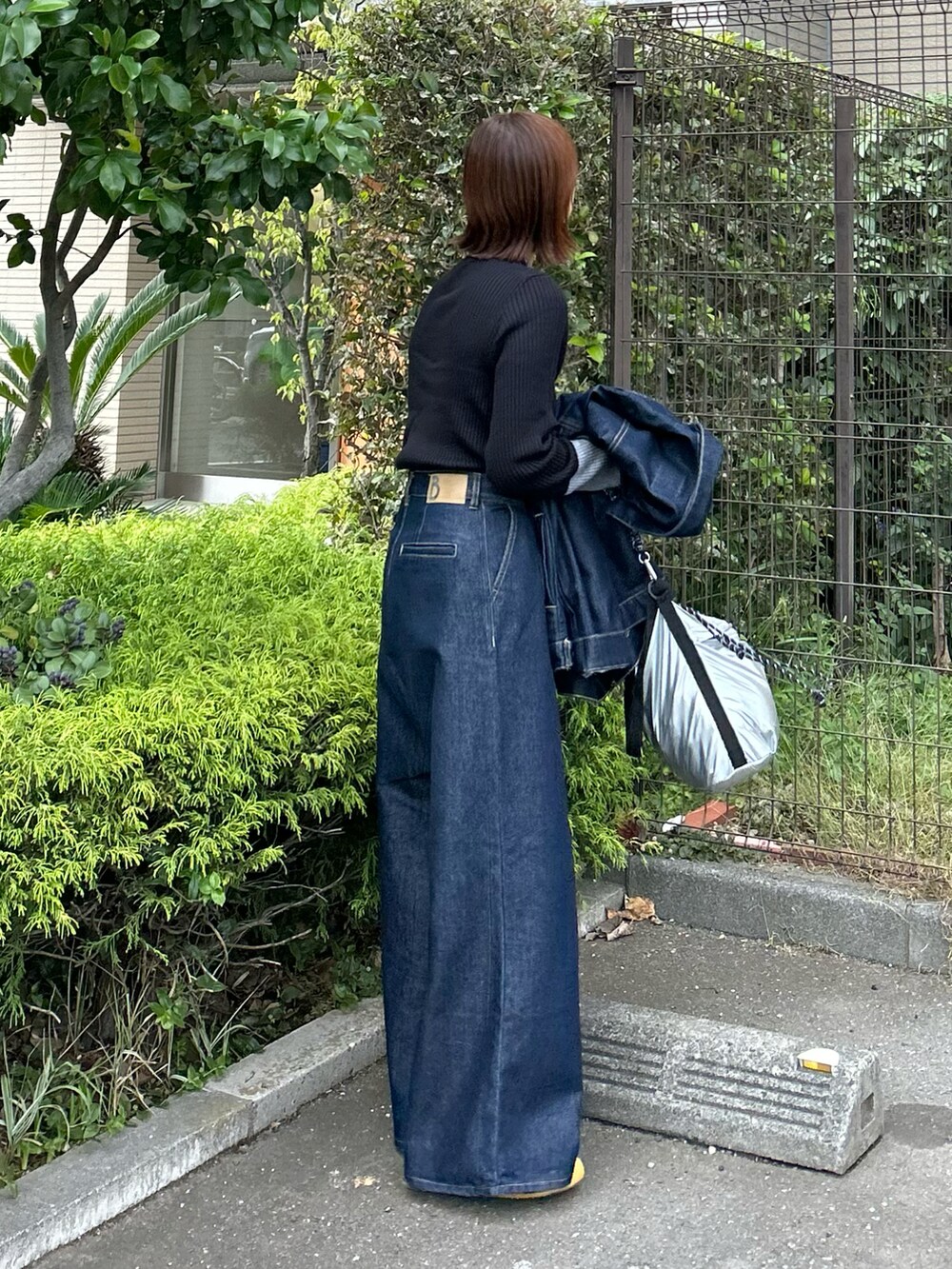 ホワイト系のダウンベスト、ブラック系のニット/セーター、ブルー系のデニムパンツを着用したレディースの秋コーディネートの4枚目の写真