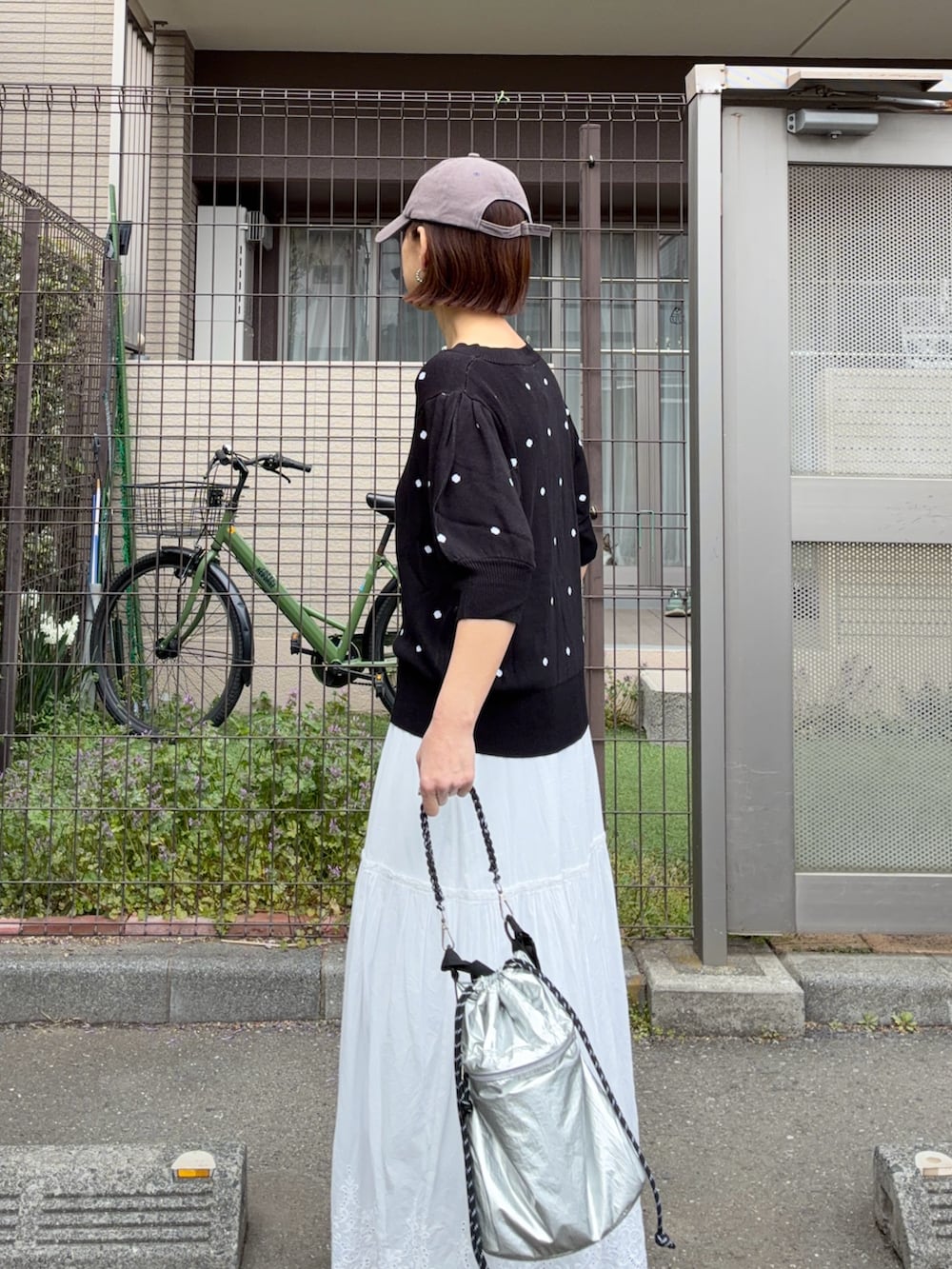 ブラック系のニット/セーター、ホワイト系のスカート、シルバー系のトートバッグを着用したレディースの春コーディネートの2枚目の写真