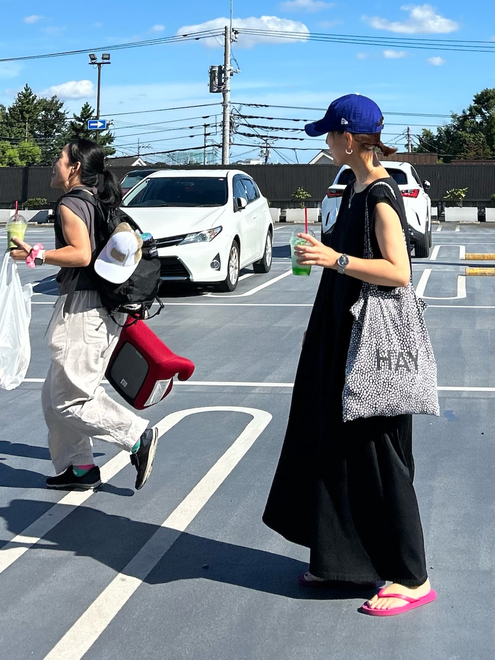 ブラック系のワンピース、パープル系のサンダル、ブルー系のキャップを着用したレディースの夏コーディネートの2枚目の写真