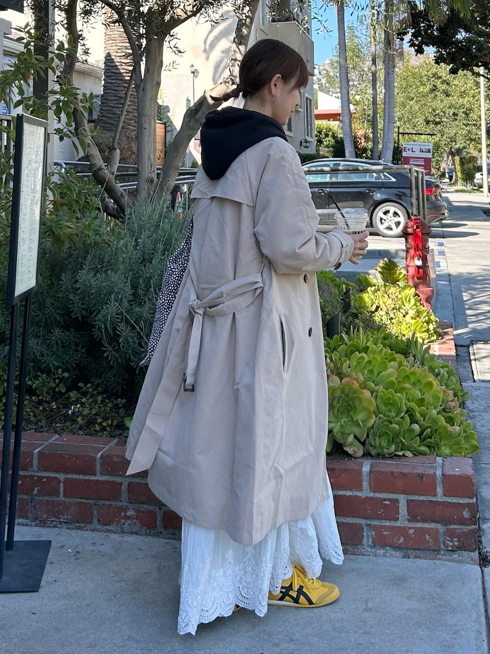 ベージュ系のトレンチコート、ブラック系のパーカー、ホワイト系のスカートを着用したレディースの冬コーディネートの4枚目の写真