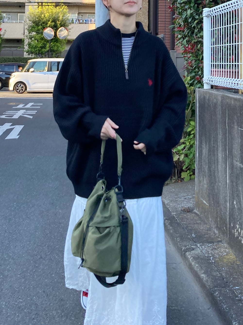 ブラック系のニット/セーター、ホワイト系のスカート、グリーン系のショルダーバッグを着用したレディースの秋コーディネートの5枚目の写真