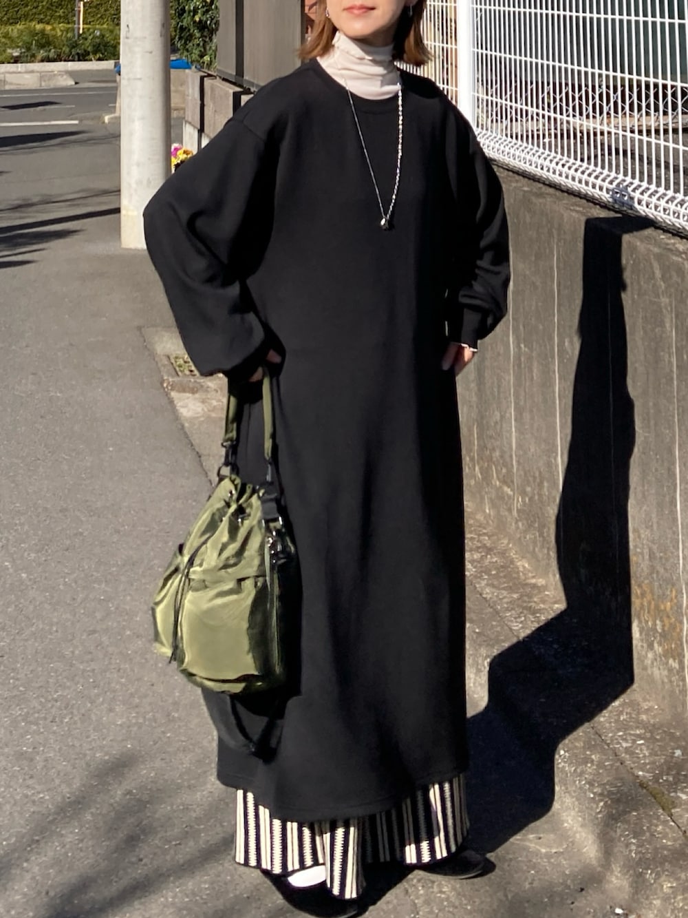 ブラック系のワンピース、ブラック系のその他パンツ、グリーン系のショルダーバッグを着用したレディースの冬コーディネートの4枚目の写真