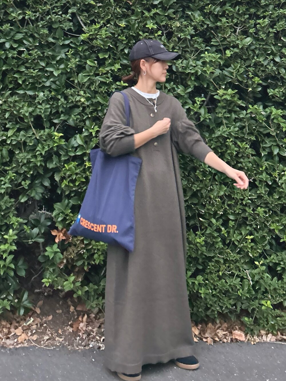グリーン系のワンピース、ブルー系のトートバッグ、ブラック系のスニーカーを着用したレディースの秋コーディネートの4枚目の写真