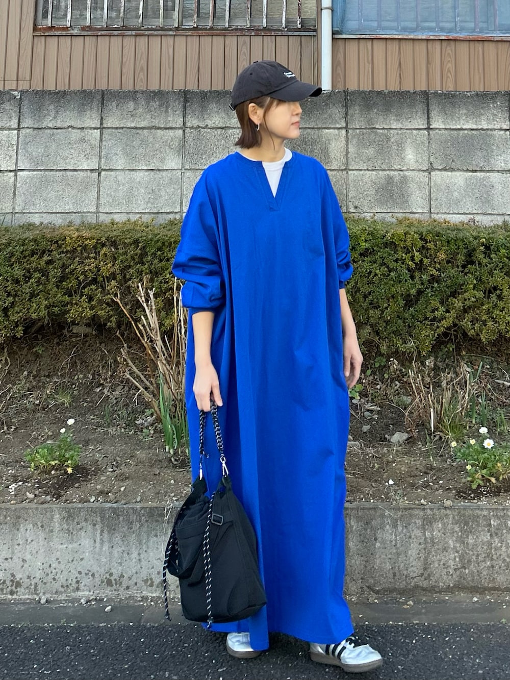 ブラック系のトートバッグ、ブルー系のワンピース、シルバー系のスニーカーを着用したレディースの冬コーディネートの2枚目の写真