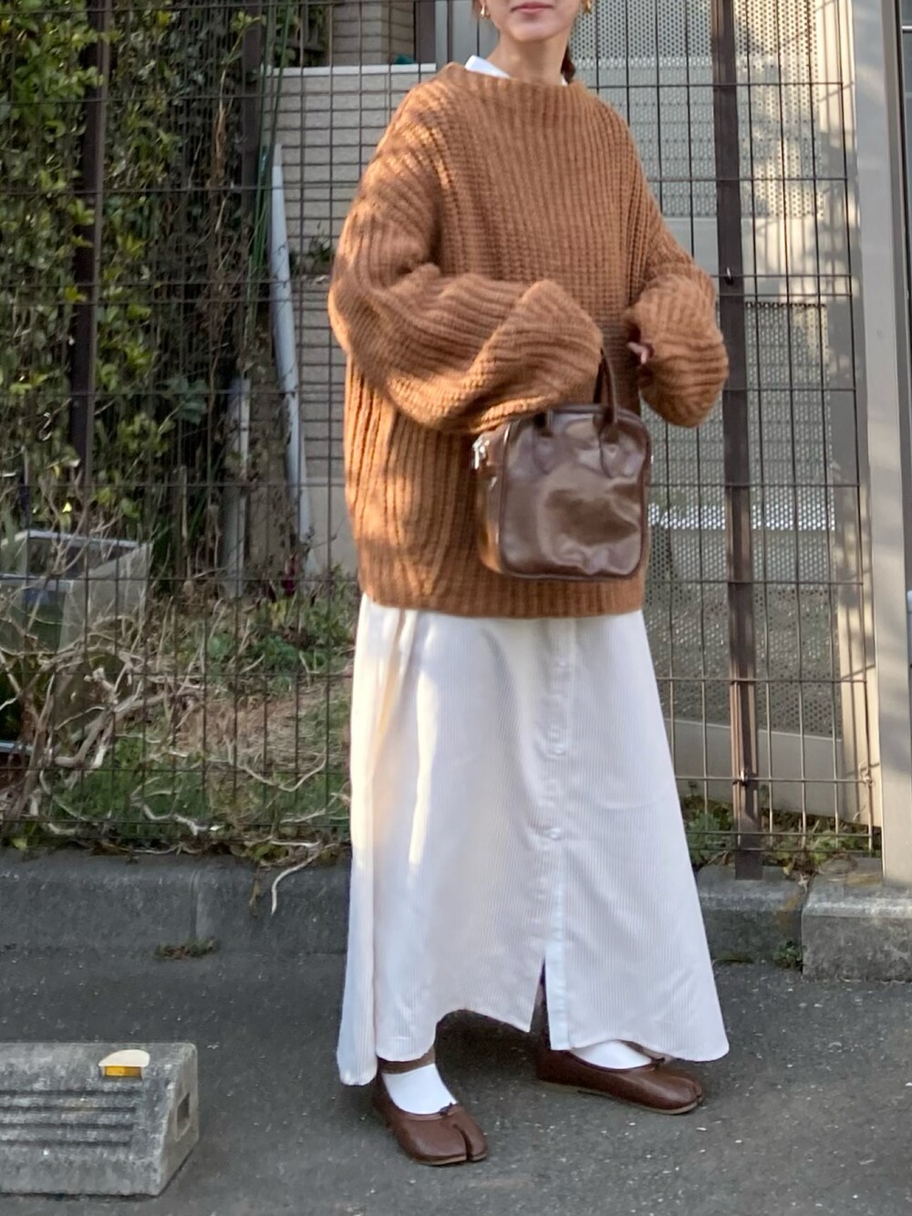 レッド系のニット/セーター、ベージュ系のワンピース、ブラウン系のショルダーバッグを着用したレディースの冬コーディネートの4枚目の写真