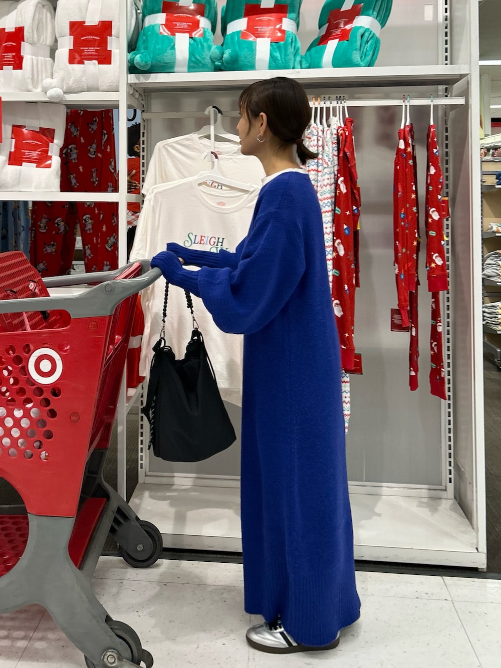 ブルー系のワンピース、ブラック系のトートバッグ、シルバー系のスニーカーを着用したレディースの冬コーディネートの2枚目の写真