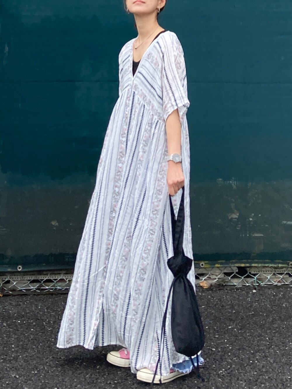 ホワイト系のワンピース、ブラック系のトートバッグ、ブルー系のデニムパンツを着用したレディースの春コーディネートの2枚目の写真