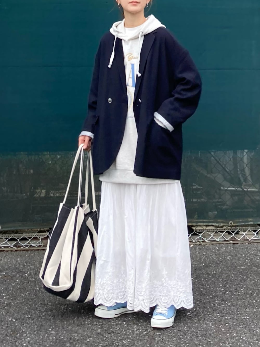 ベージュ系のパーカー、ホワイト系のスカート、ブラック系のトートバッグを着用したレディースの春コーディネートの4枚目の写真