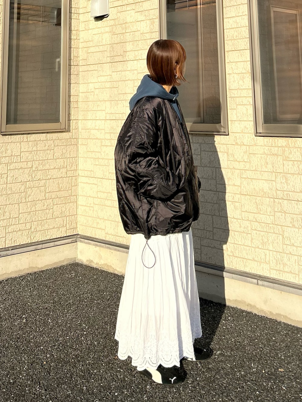 ブラック系のブルゾン、ブルー系のパーカー、シルバー系のトートバッグを着用したレディースの冬コーディネートの2枚目の写真