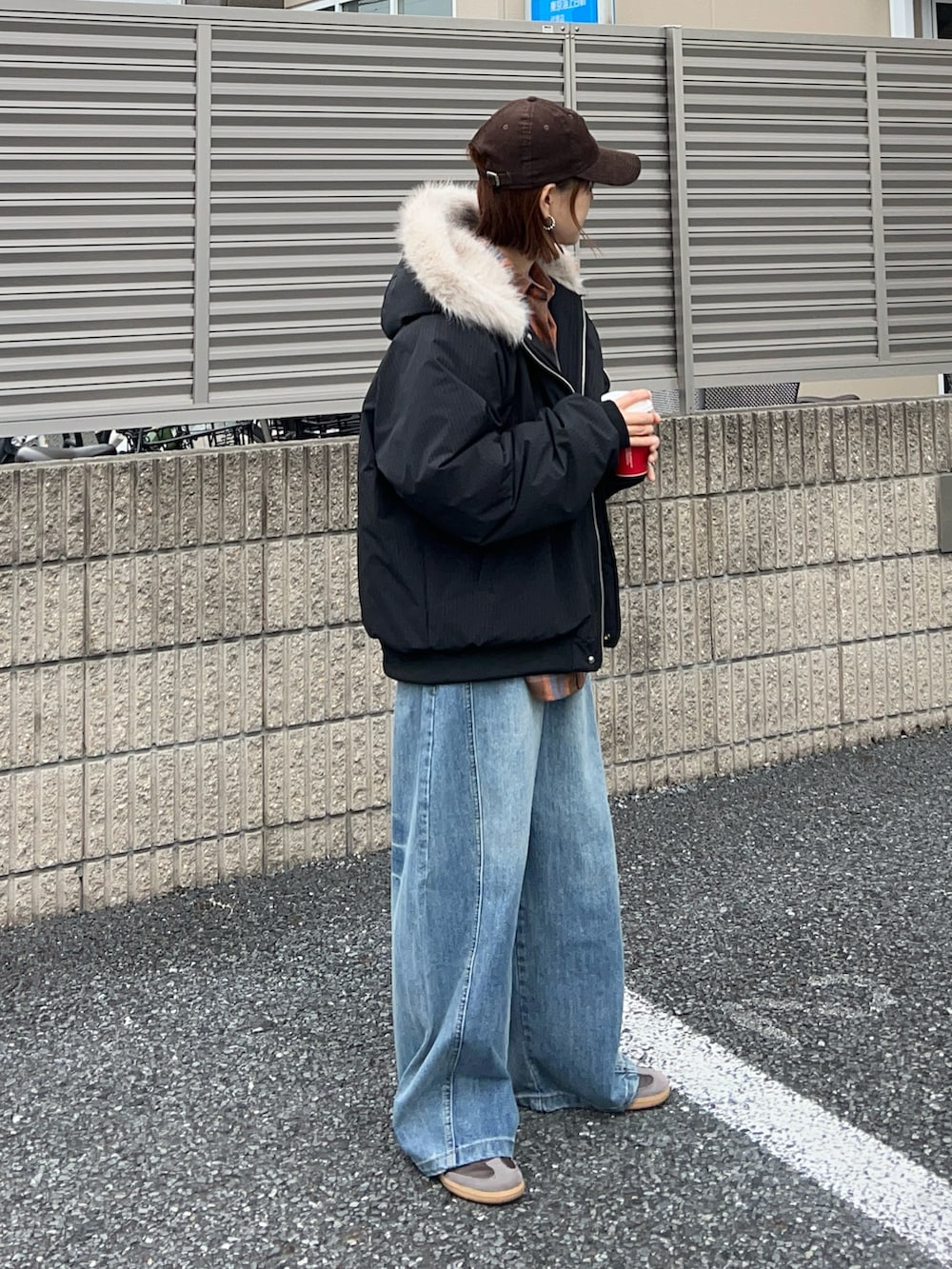 オレンジ系のショルダーバッグ、ブラウン系のスニーカー、ブラック系のその他アウターを着用したレディースの冬コーディネートの2枚目の写真