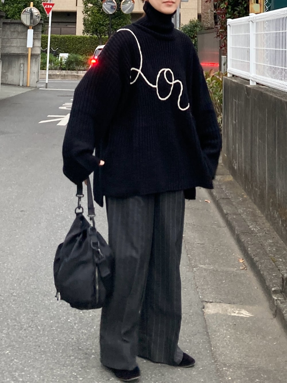 ブラック系のニット/セーター、グレー系のパンツ、ブラック系のショルダーバッグを着用したレディースの冬コーディネートの2枚目の写真