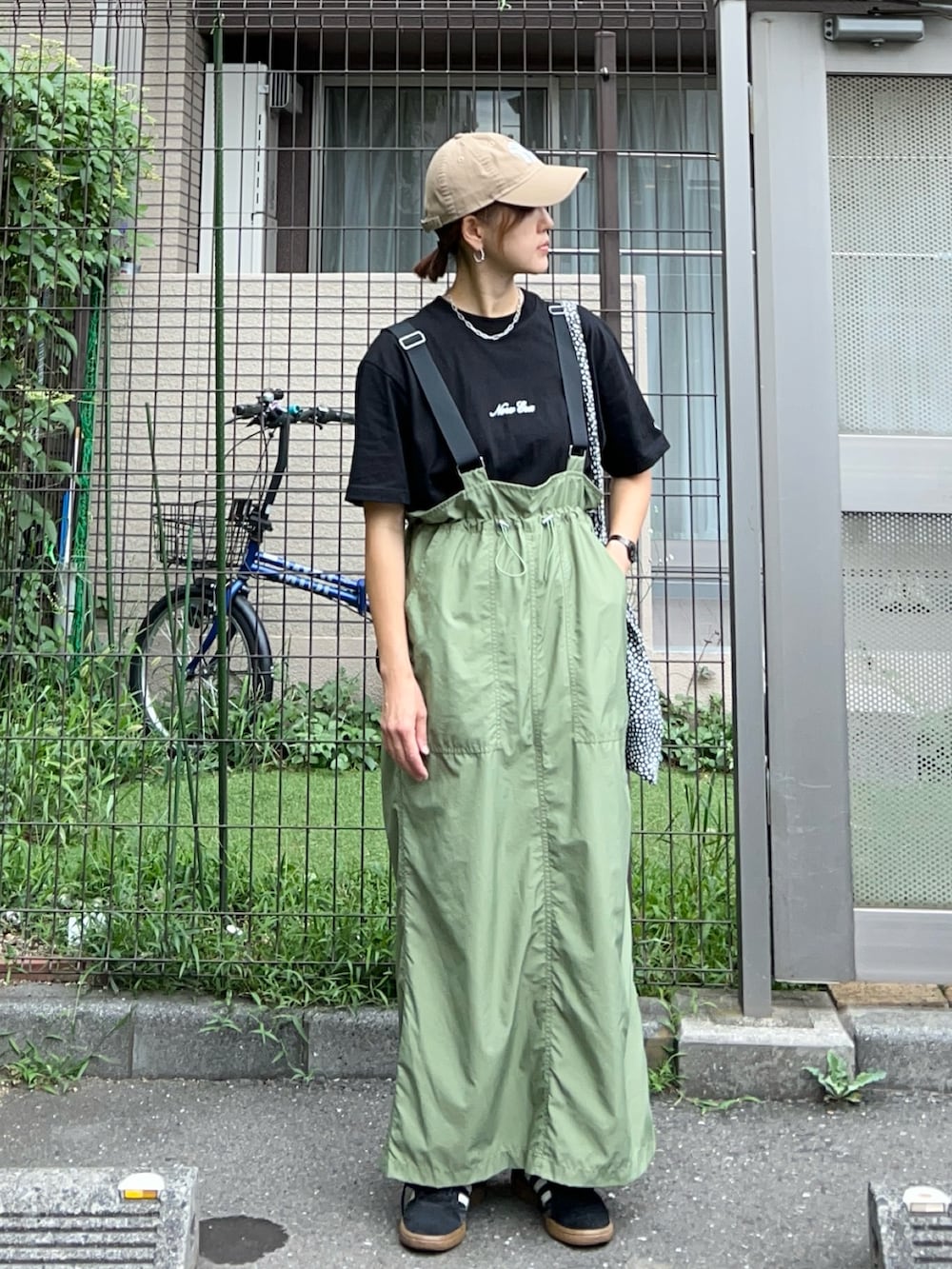 ブラック系のTシャツ/カットソー、グリーン系のジャンパースカート、ブラック系のスニーカーを着用したレディースの秋コーディネートの2枚目の写真