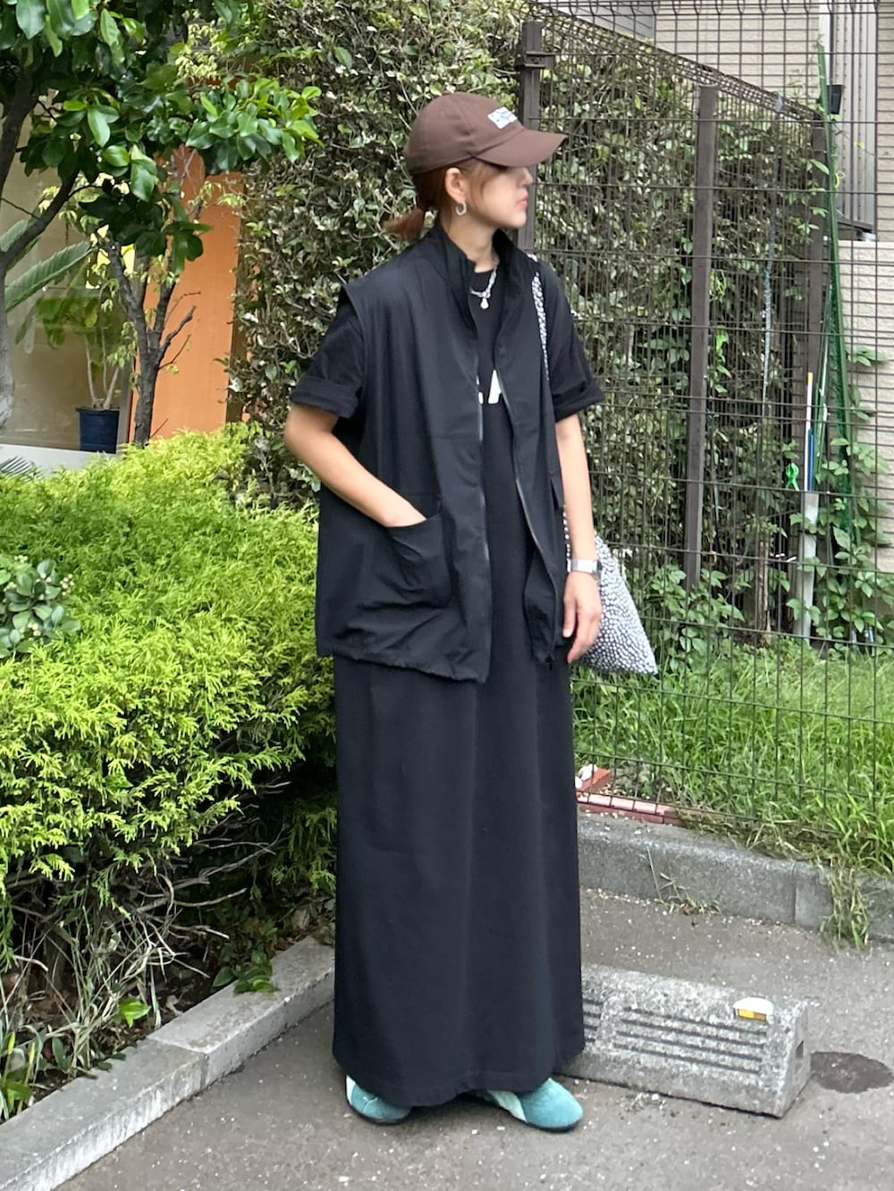 ブラック系のベスト、ブラック系のワンピース、グリーン系のスニーカーを着用したレディースの秋コーディネートの3枚目の写真