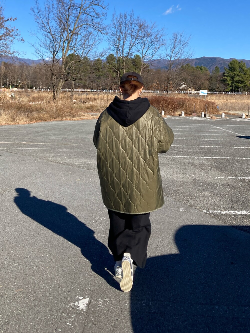 ブラック系のワンピース、ブラック系のショルダーバッグ、グリーン系のノーカラージャケットを着用したレディースの冬コーディネートの5枚目の写真