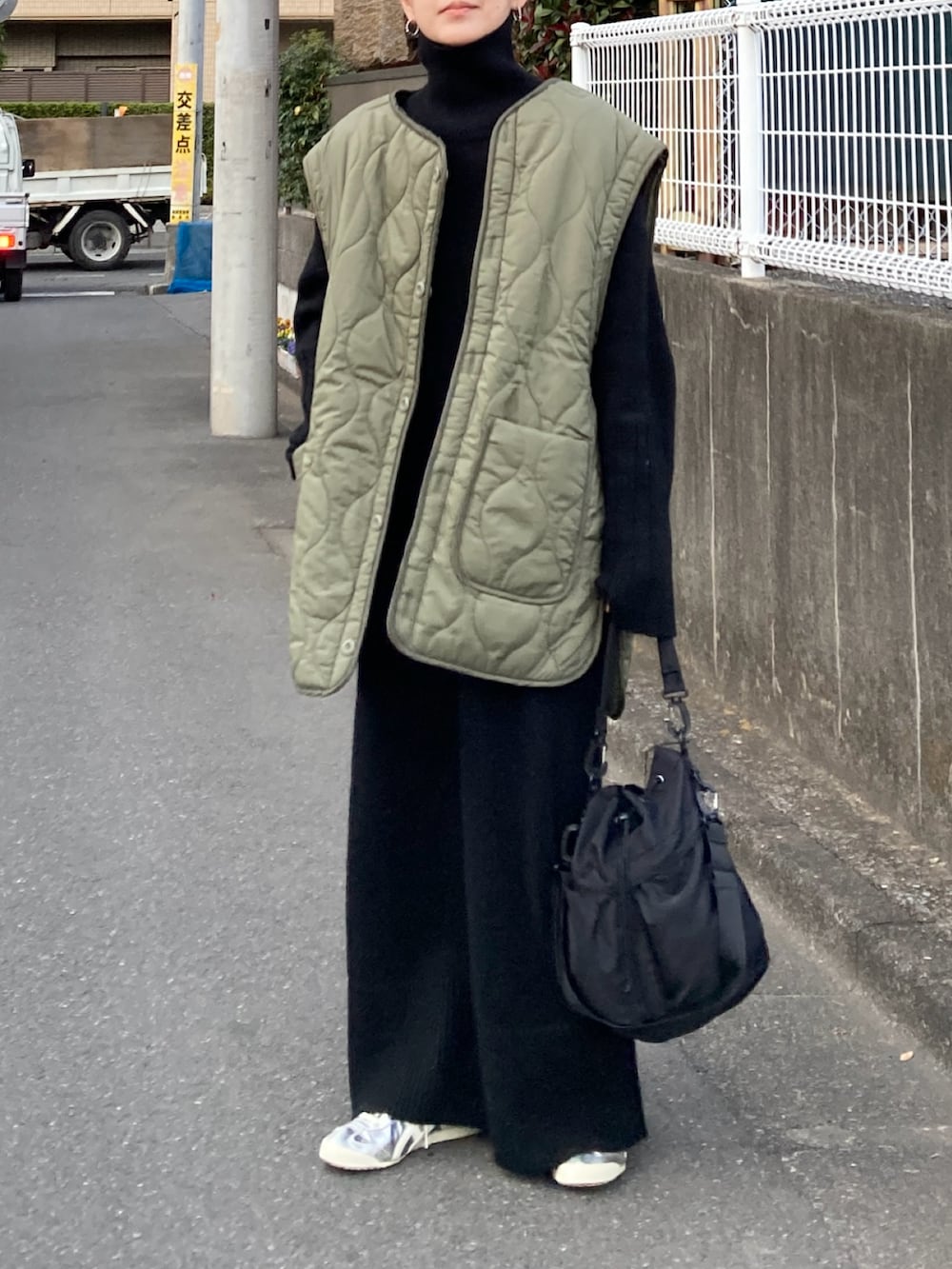 グリーン系のブルゾン、ブラック系のワンピース、ブラック系のショルダーバッグを着用したレディースの冬コーディネートの3枚目の写真