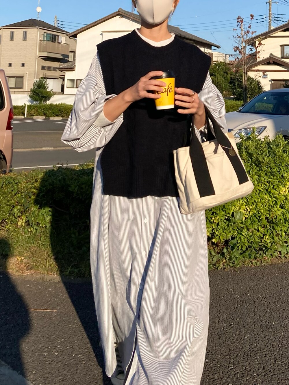 ブラック系のベスト、ブラック系のワンピース、ホワイト系のトートバッグを着用したレディースの秋コーディネートの3枚目の写真