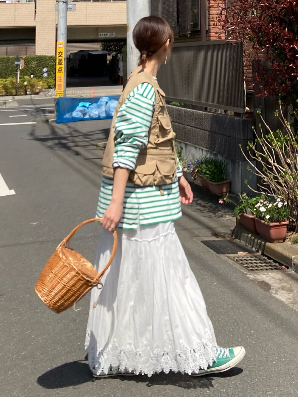 グリーン系のTシャツ/カットソー、ベージュ系のベスト、ホワイト系のスカートを着用したレディースの春コーディネートの4枚目の写真