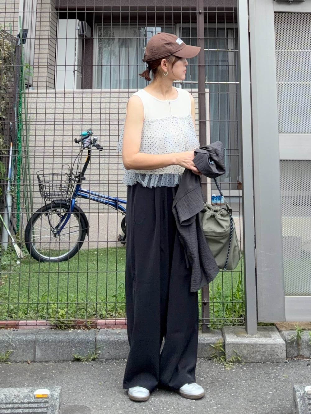 ホワイト系のニット/セーター、ブラック系のスラックス、シルバー系のスニーカーを着用したレディースの夏コーディネートの2枚目の写真
