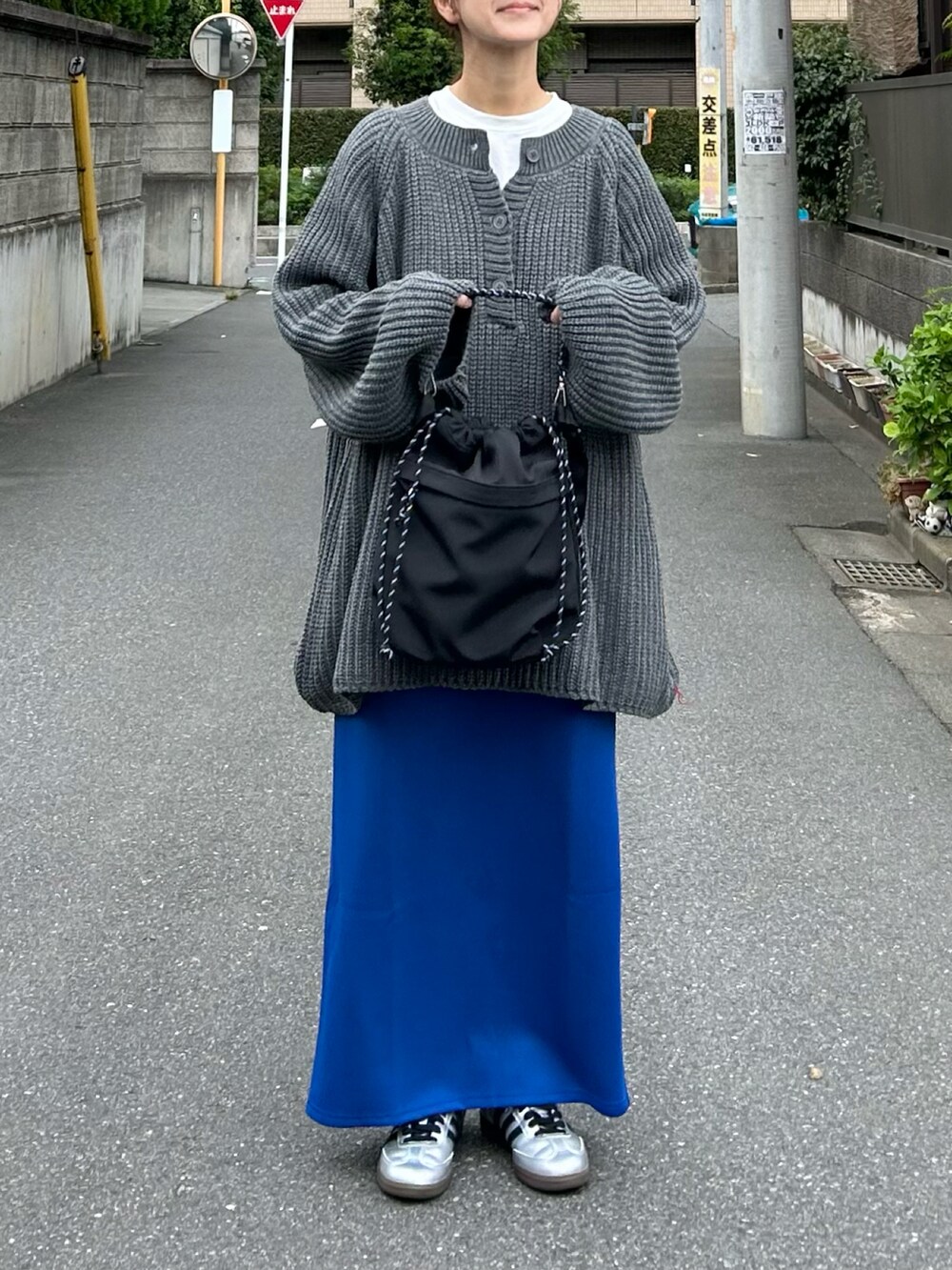 グレー系のニット/セーター、ブラック系のショルダーバッグ、ブルー系のスカートを着用したレディースの秋コーディネートの5枚目の写真