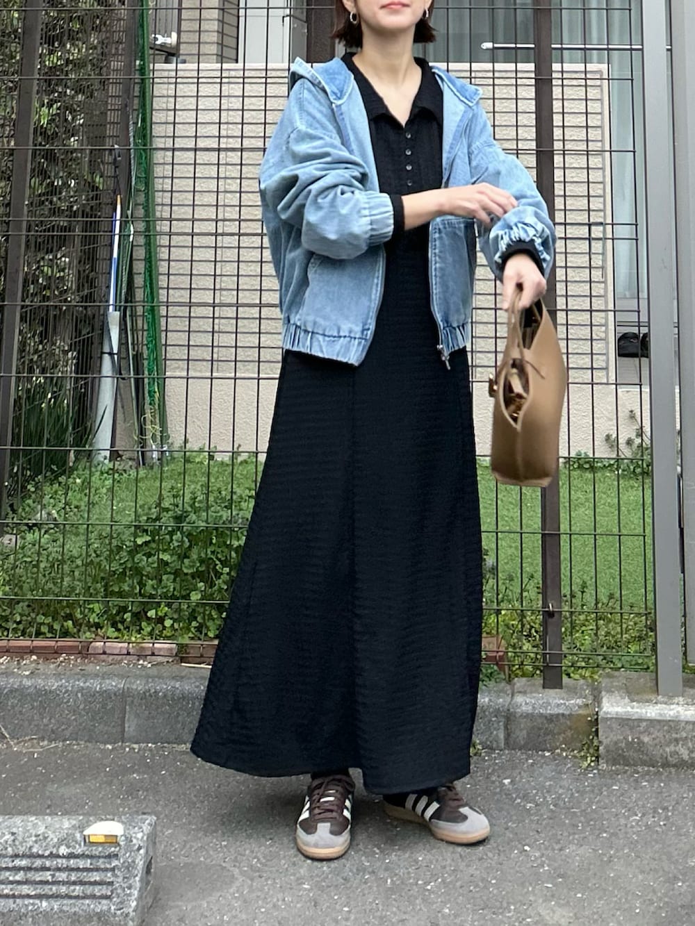 ブルー系のデニムジャケット、ブラック系のワンピース、ブラウン系のハンドバッグを着用したレディースの冬コーディネートの2枚目の写真