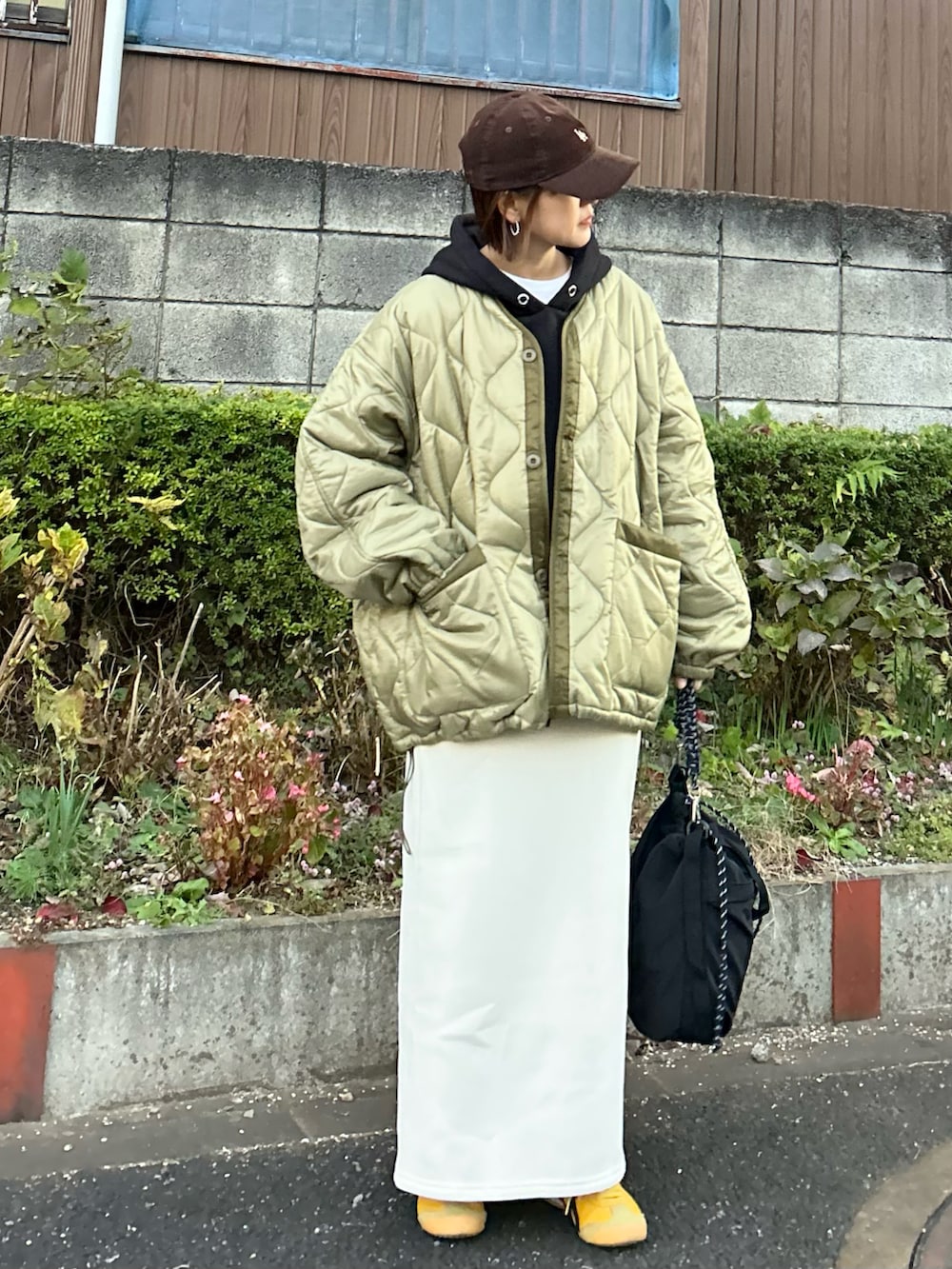 ブラック系のパーカー、ホワイト系のスカート、ブラック系のトートバッグを着用したレディースの冬コーディネートの2枚目の写真