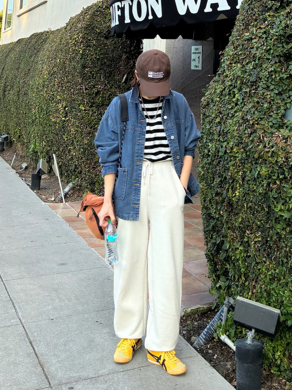 ブラック系のTシャツ/カットソー、オレンジ系のショルダーバッグ、ブルー系のデニムジャケットを着用したレディースの春コーディネートの2枚目の写真