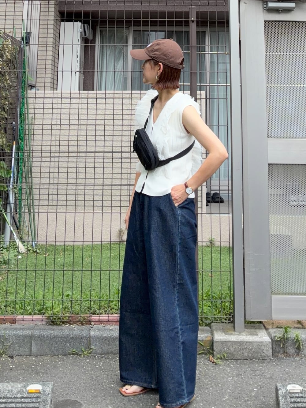 ブラック系のボディバッグ/ウエストポーチ、ホワイト系のカーディガン/ボレロ、ブルー系のデニムパンツを着用したレディースの夏コーディネートの3枚目の写真