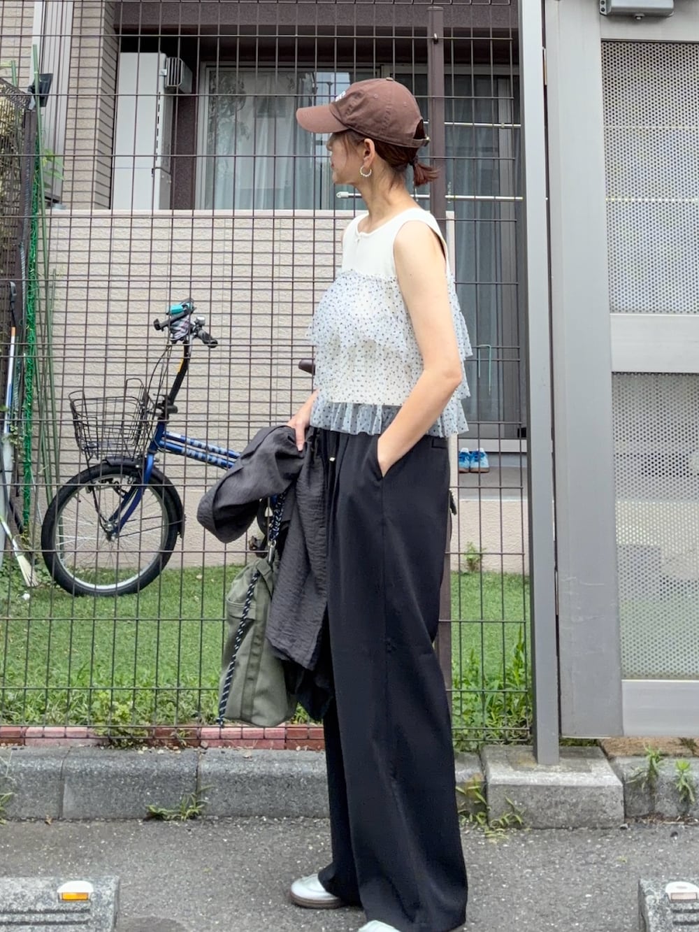 ホワイト系のニット/セーター、ブラック系のスラックス、シルバー系のスニーカーを着用したレディースの夏コーディネートの3枚目の写真