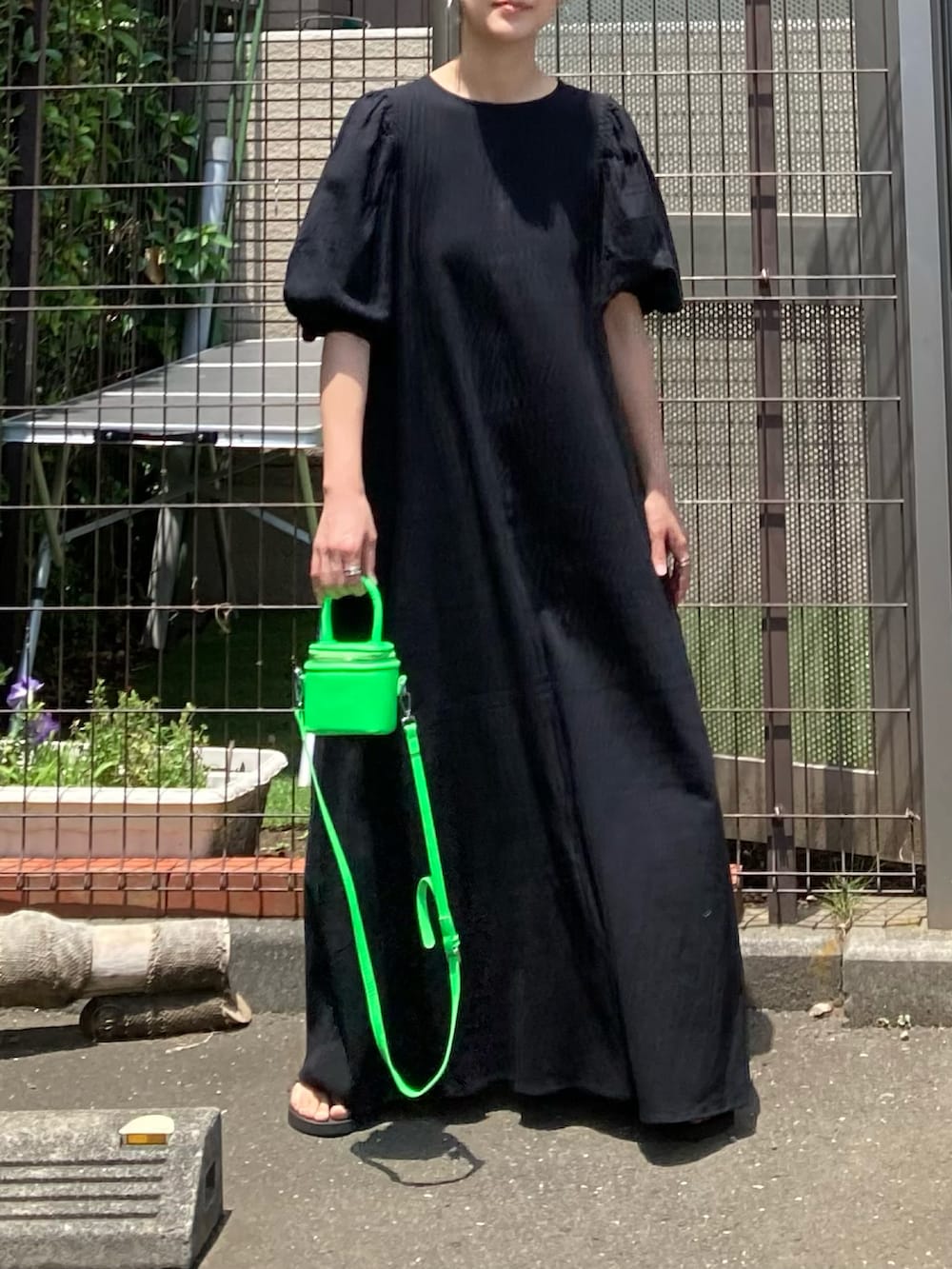 ブラック系のワンピース、グリーン系のショルダーバッグ、シルバー系のピアス（両耳用）を着用したレディースの夏コーディネートの2枚目の写真