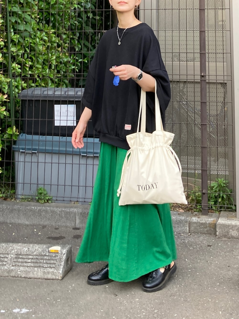 ブラック系のスウェット、ホワイト系のトートバッグ、グリーン系のスカートを着用したレディースの秋コーディネートの2枚目の写真