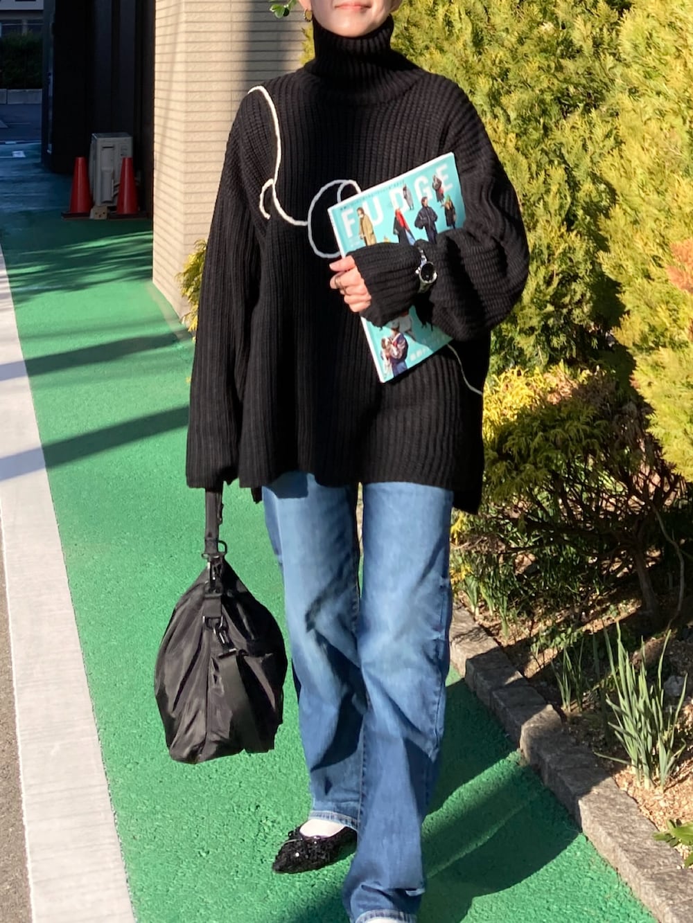 ブラック系のニット/セーター、ブルー系のデニムパンツ、ブラック系のショルダーバッグを着用したレディースの冬コーディネートの2枚目の写真