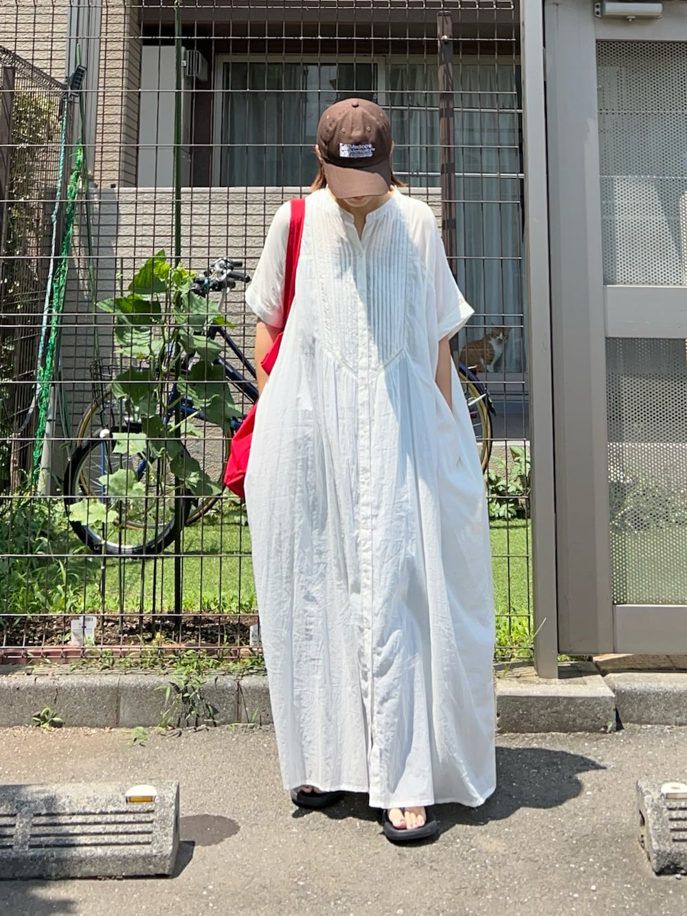 ブルー系のデニムパンツ、ホワイト系のワンピース、レッド系のトートバッグを着用したレディースの夏コーディネートの2枚目の写真