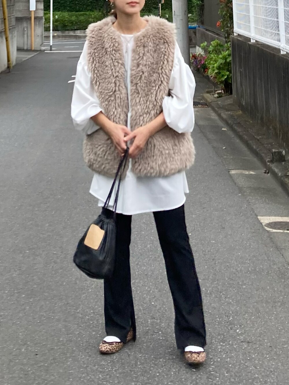 ベージュ系のベスト、ホワイト系のシャツ/ブラウス、ブラック系のハンドバッグを着用したレディースの秋コーディネートの5枚目の写真