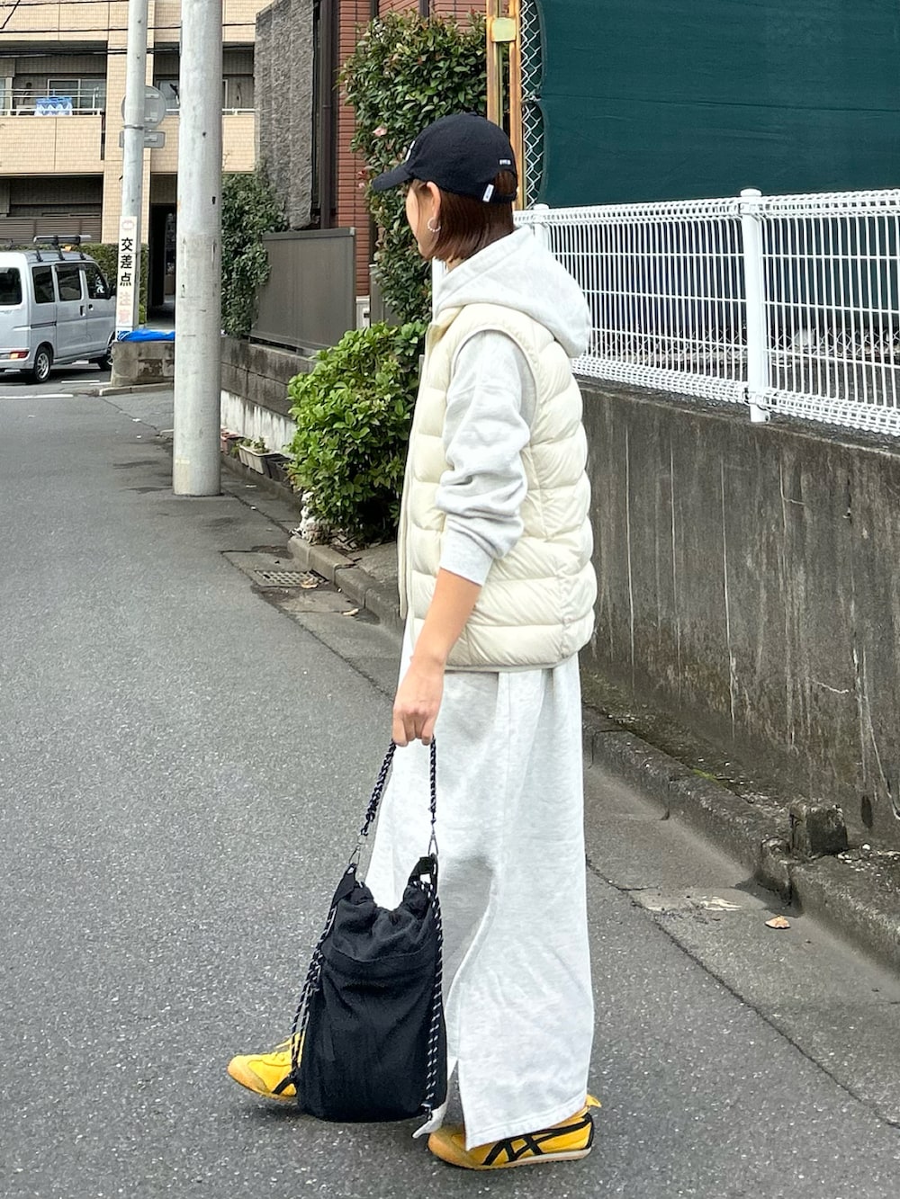 ホワイト系のダウンベスト、ブラック系のショルダーバッグ、グレー系のワンピースを着用したレディースの秋コーディネートの2枚目の写真