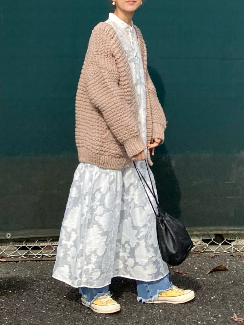 ホワイト系のワンピース、ベージュ系のカーディガン/ボレロ、ブルー系のデニムパンツを着用したレディースの秋コーディネートの2枚目の写真