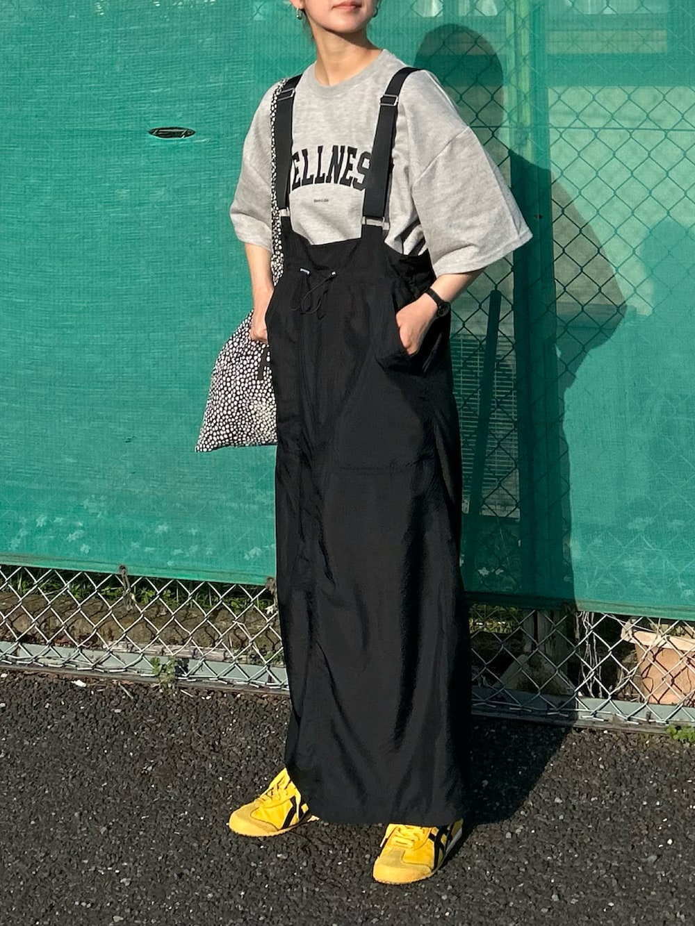 グレー系のTシャツ/カットソー、ブラック系のジャンパースカート、ブラック系のトートバッグを着用したレディースの春コーディネートの3枚目の写真