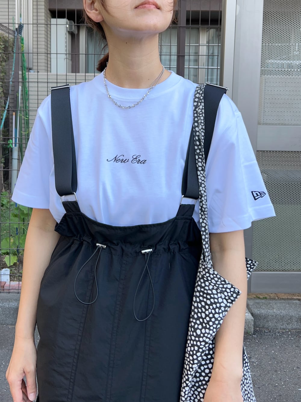 ブラック系のジャンパースカート、ホワイト系のTシャツ/カットソー、グリーン系のスニーカーを着用したレディースの夏コーディネートの3枚目の写真