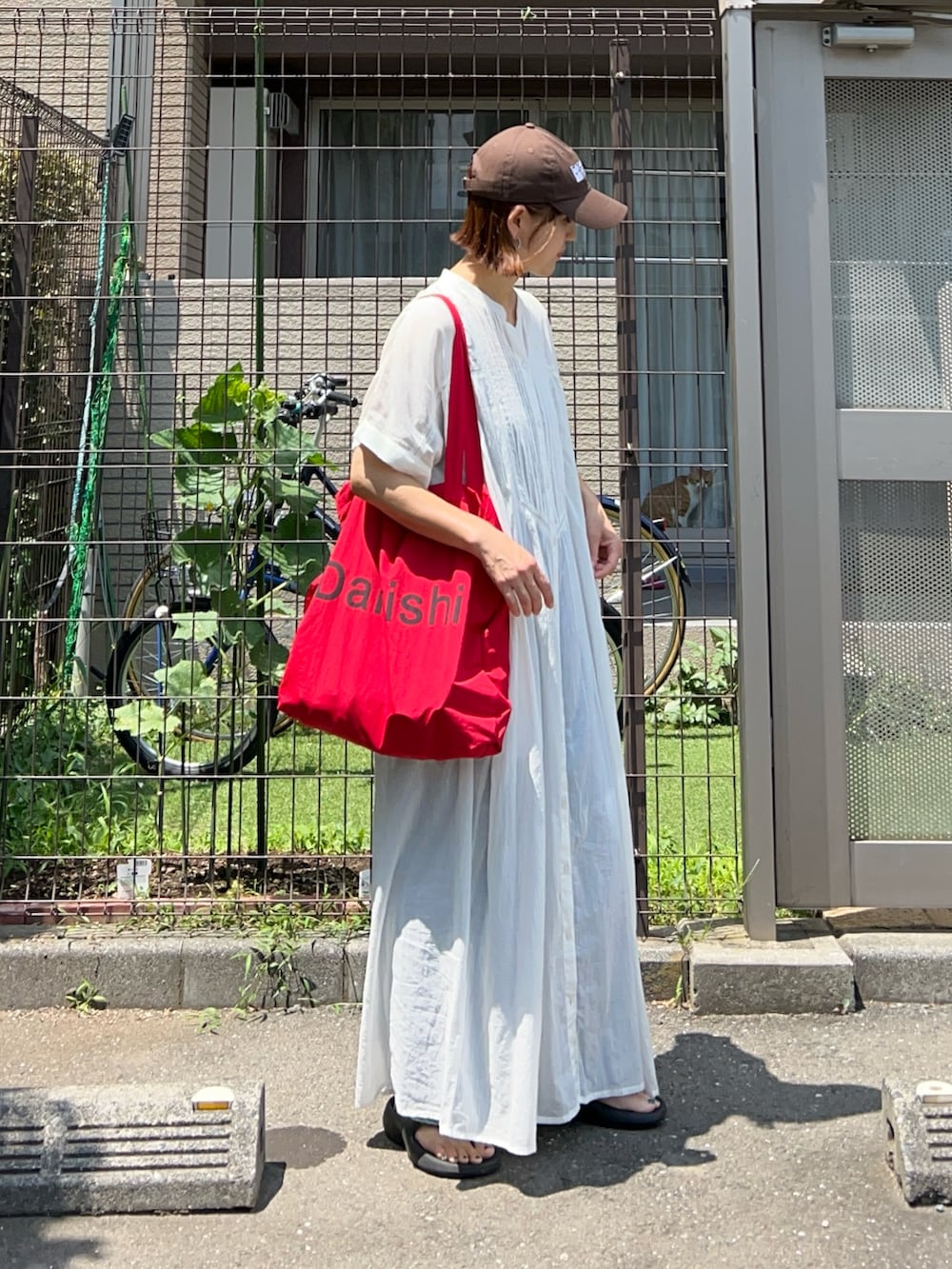 ブルー系のデニムパンツ、ホワイト系のワンピース、レッド系のトートバッグを着用したレディースの夏コーディネートの3枚目の写真