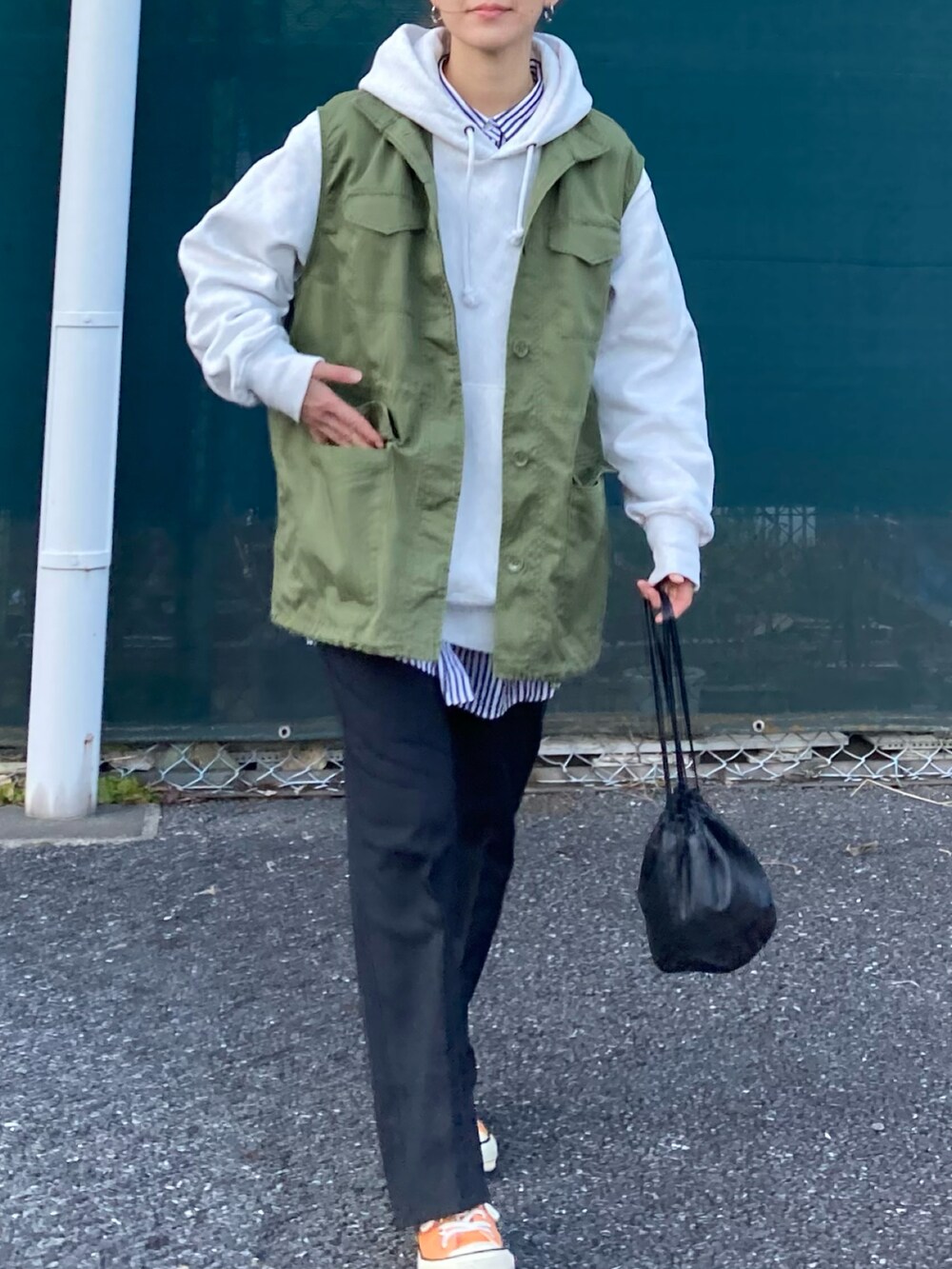 グリーン系のベスト、グレー系のパーカー、ブラック系のスラックスを着用したレディースの冬コーディネートの4枚目の写真