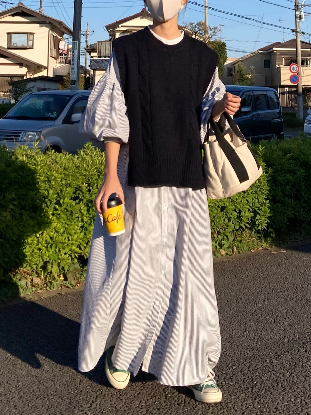 ブラック系のベスト、ブラック系のワンピース、ホワイト系のトートバッグを着用したレディースの秋コーディネートの2枚目の写真