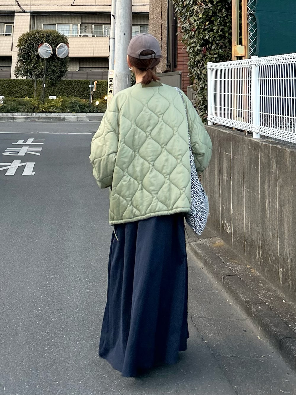 ブルー系のワンピース、グリーン系のノーカラージャケット、シルバー系のスニーカーを着用したレディースの冬コーディネートの5枚目の写真